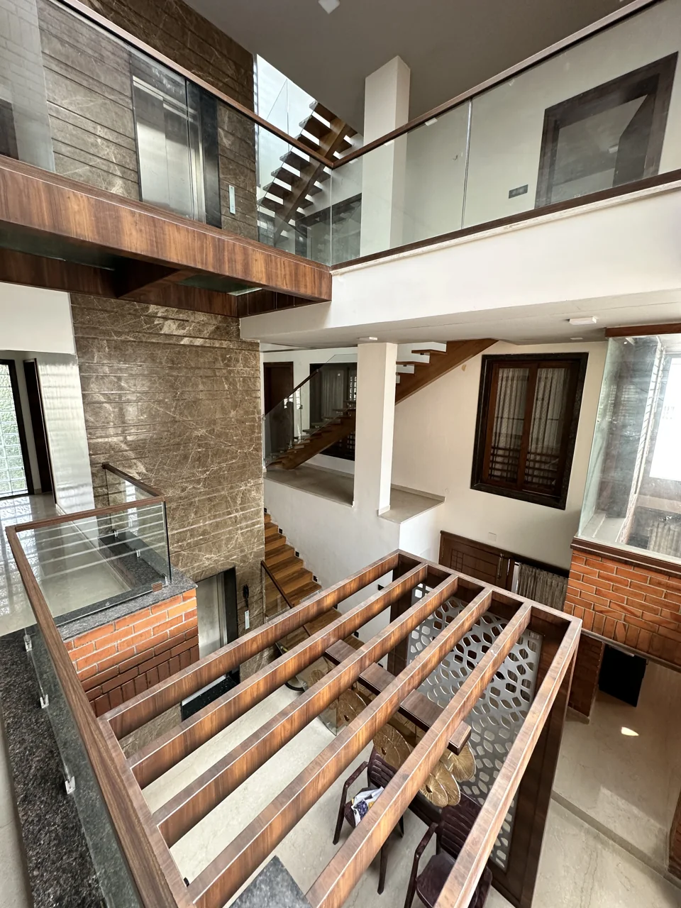 Double-height interior with brickwork, wood details, glass balustrades and overhead daylight