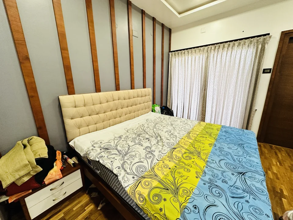 Bedroom with upholstered headboard, wood wall details and full-height curtains