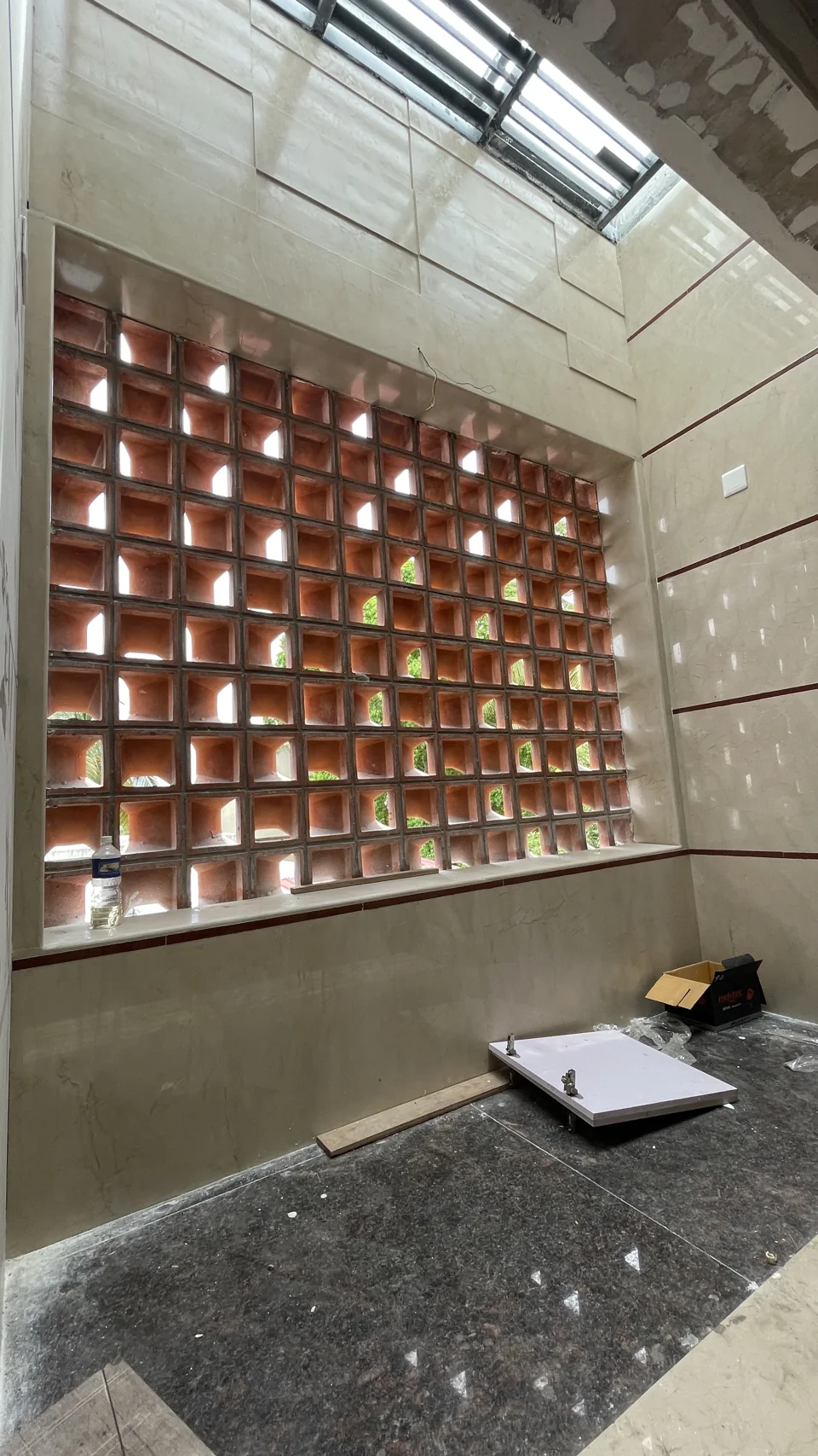Perforated brick screen admitting daylight into an interior under construction