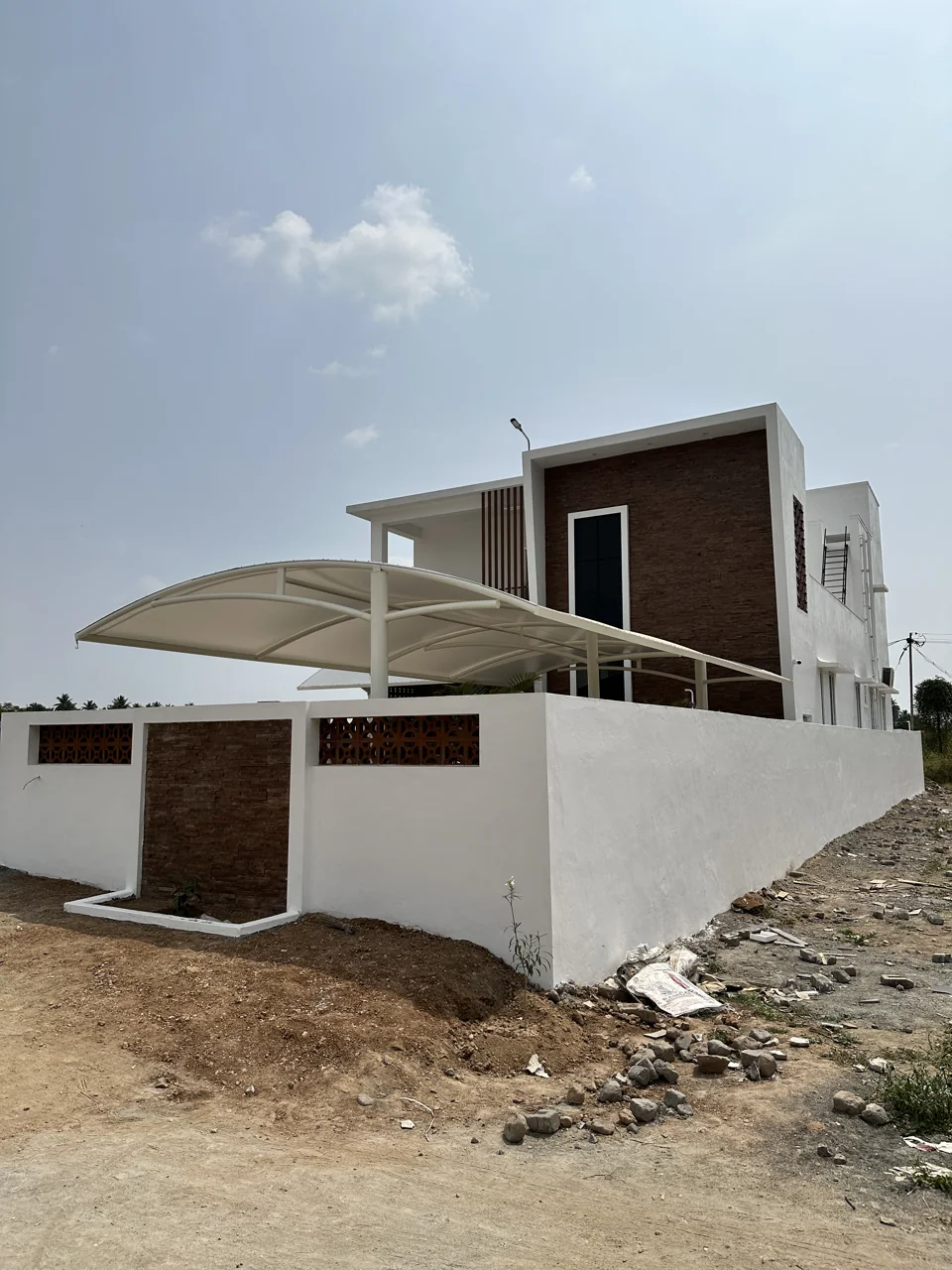 Contemporary white facade with a tall wood-toned accent and curved carport canopy
