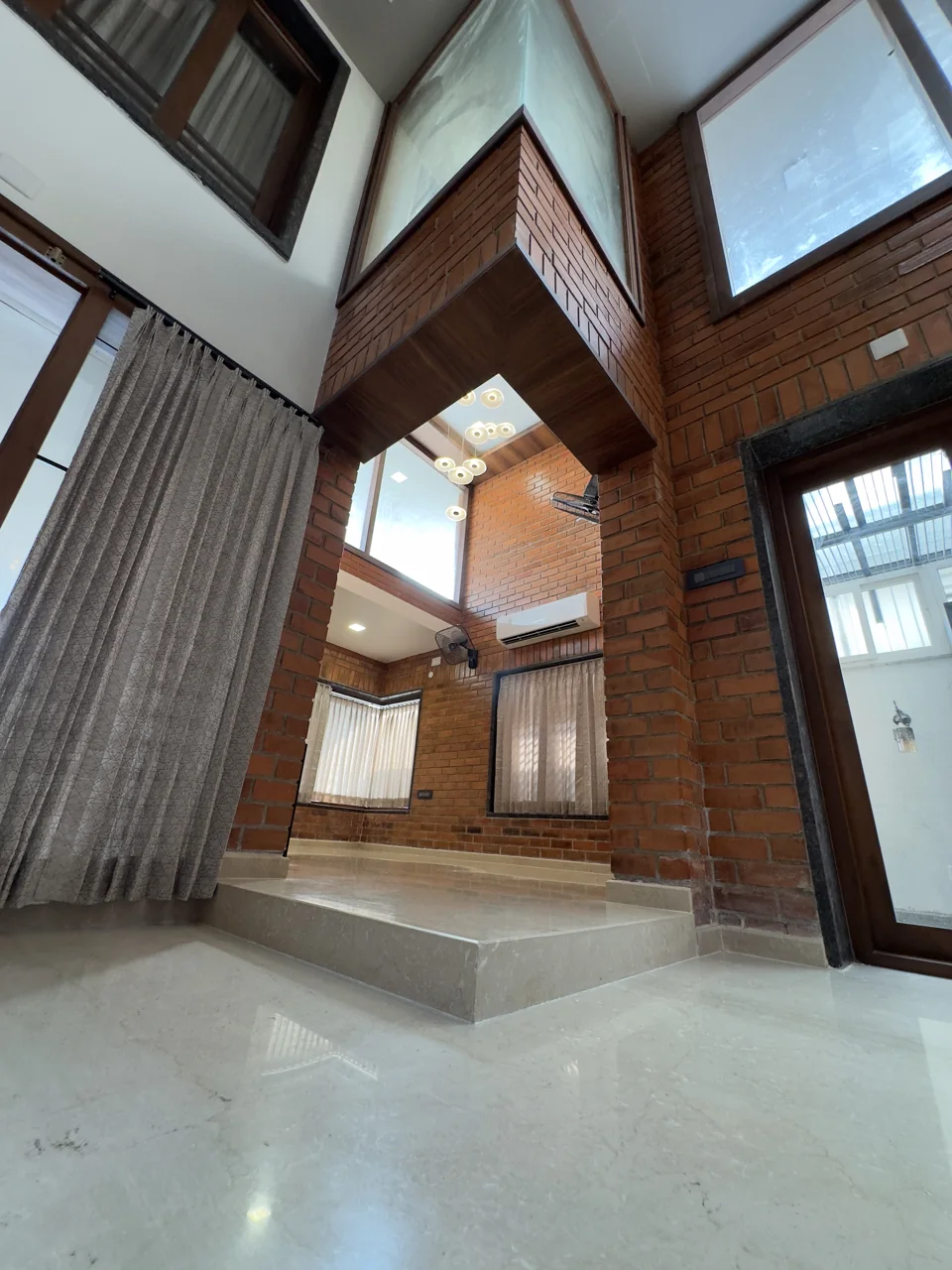 Double-height hall with brick walls, timber soffits and a raised platform