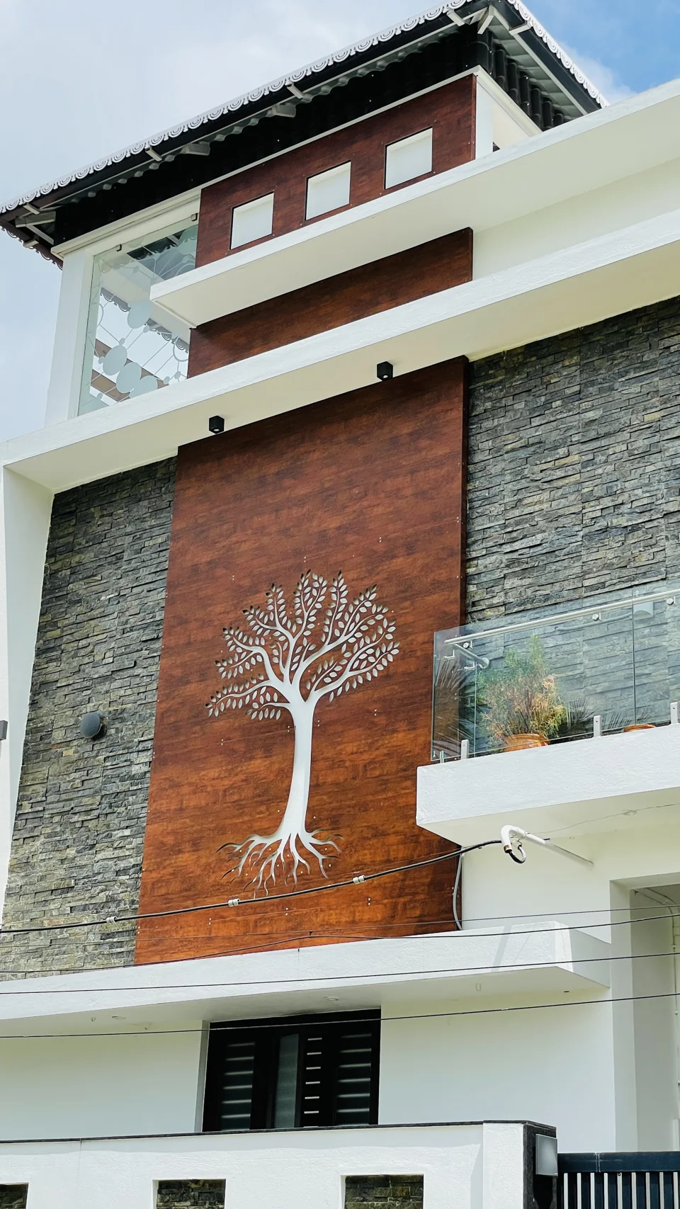 Facade detail showing brick texture, stone cladding and a white tree motif
