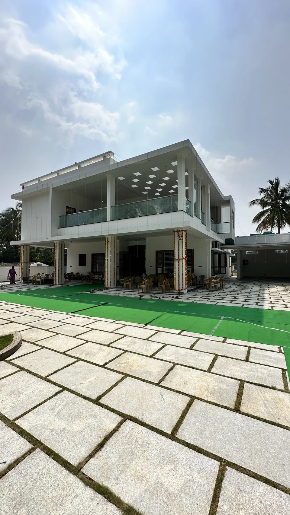 White two-storey home with a shaded balcony, lawn and stone-paved approach