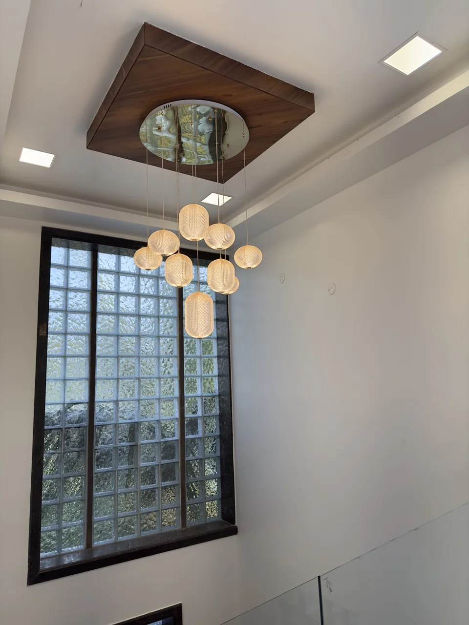 Stair hall lit through a tall glass-block window with a cluster pendant light