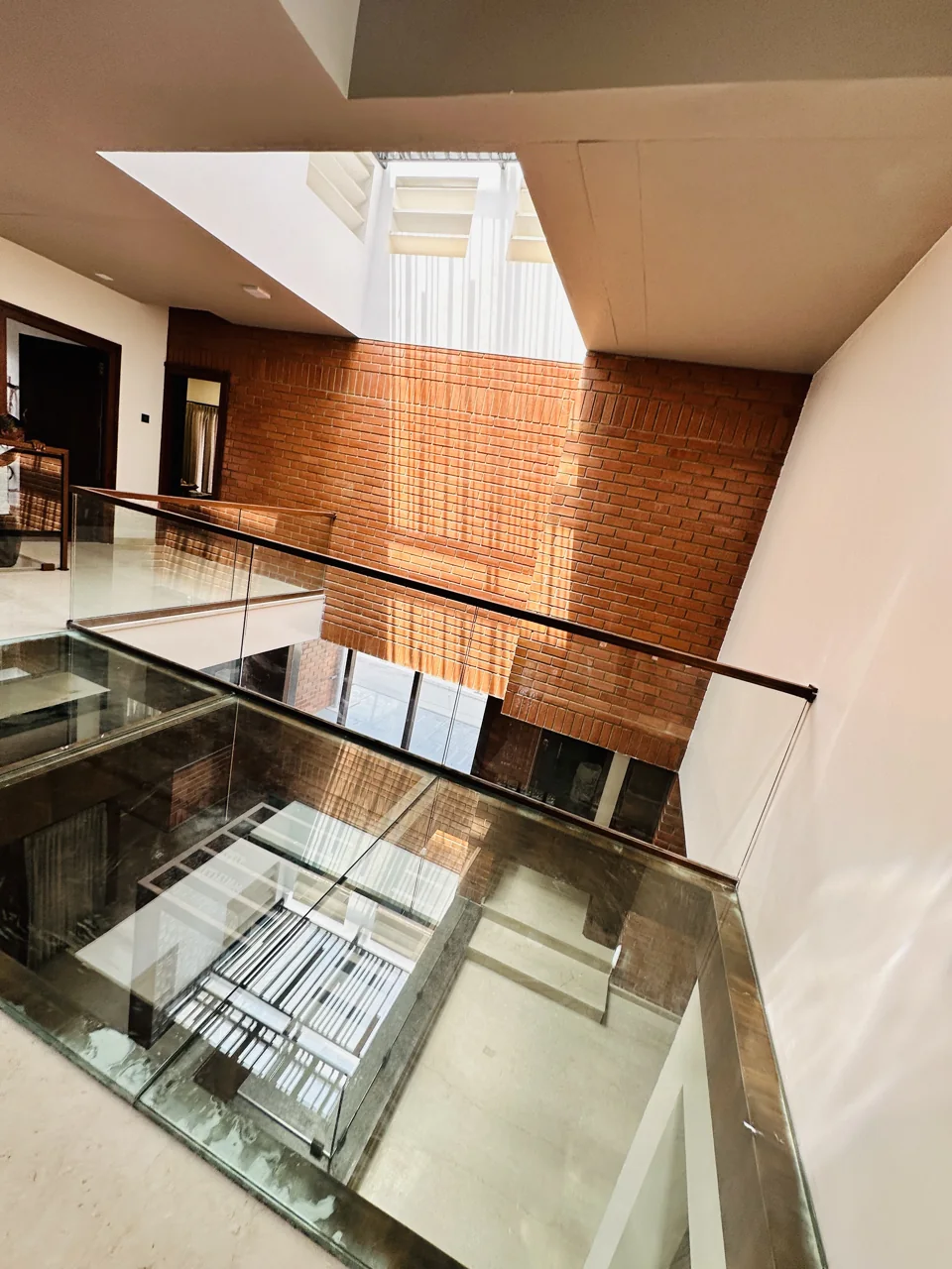 Upper-level landing with exposed brick, glass railing and a skylit central void
