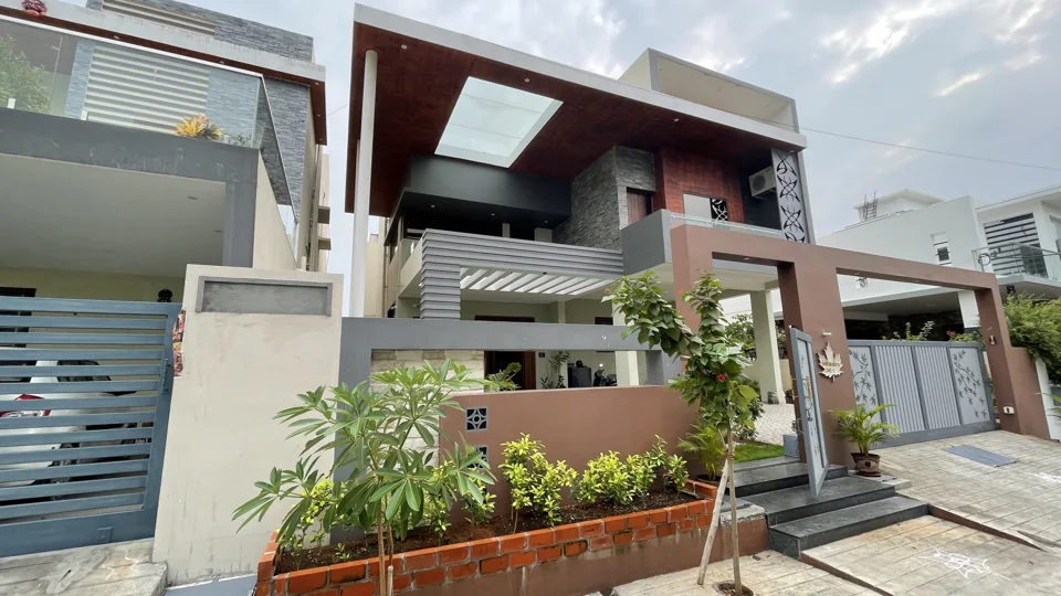 Contemporary home with a timber-toned frame, grey screens and planters along the front wall