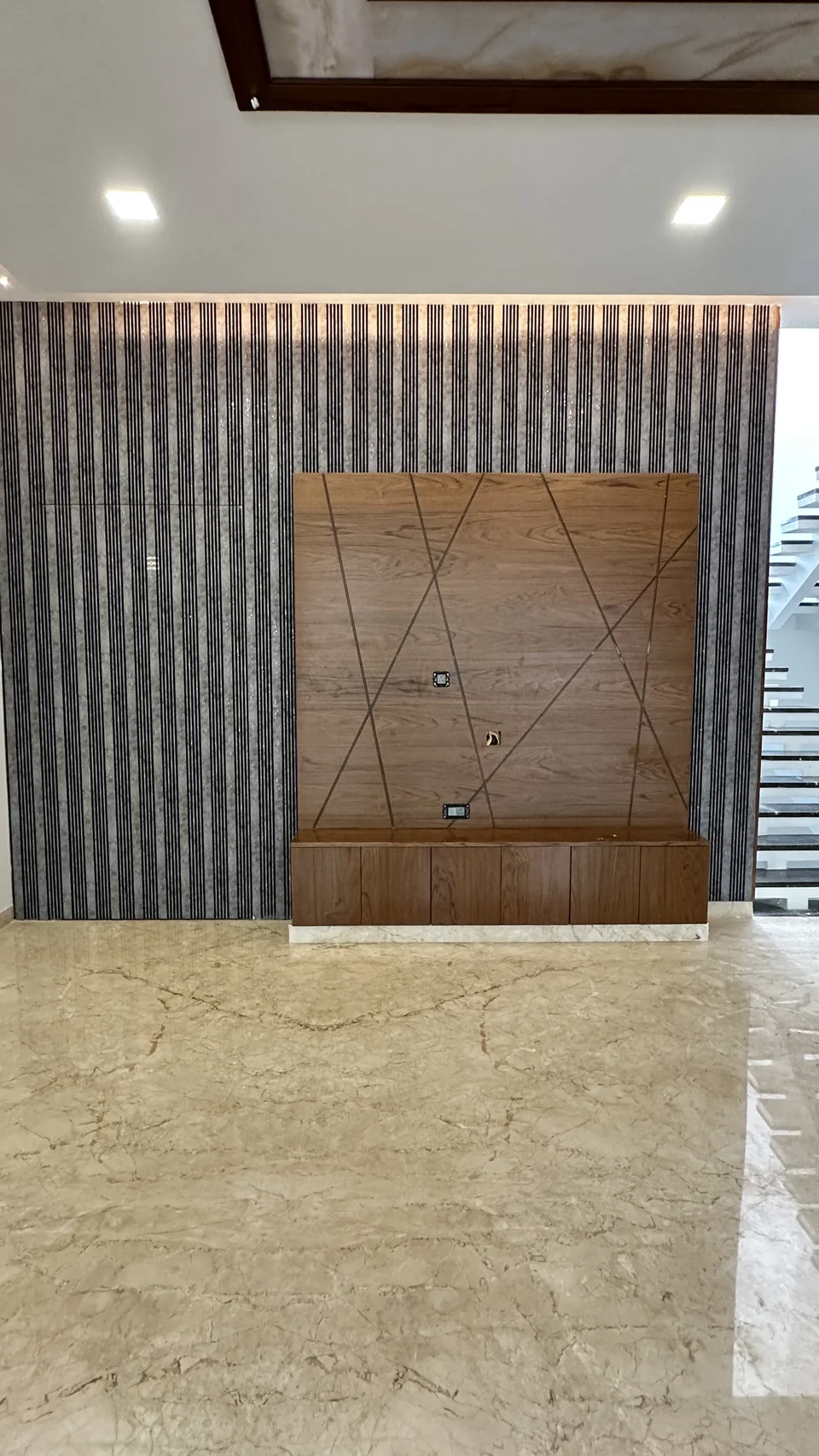Living room wall with a grey textured panel, timber inlay and marble flooring