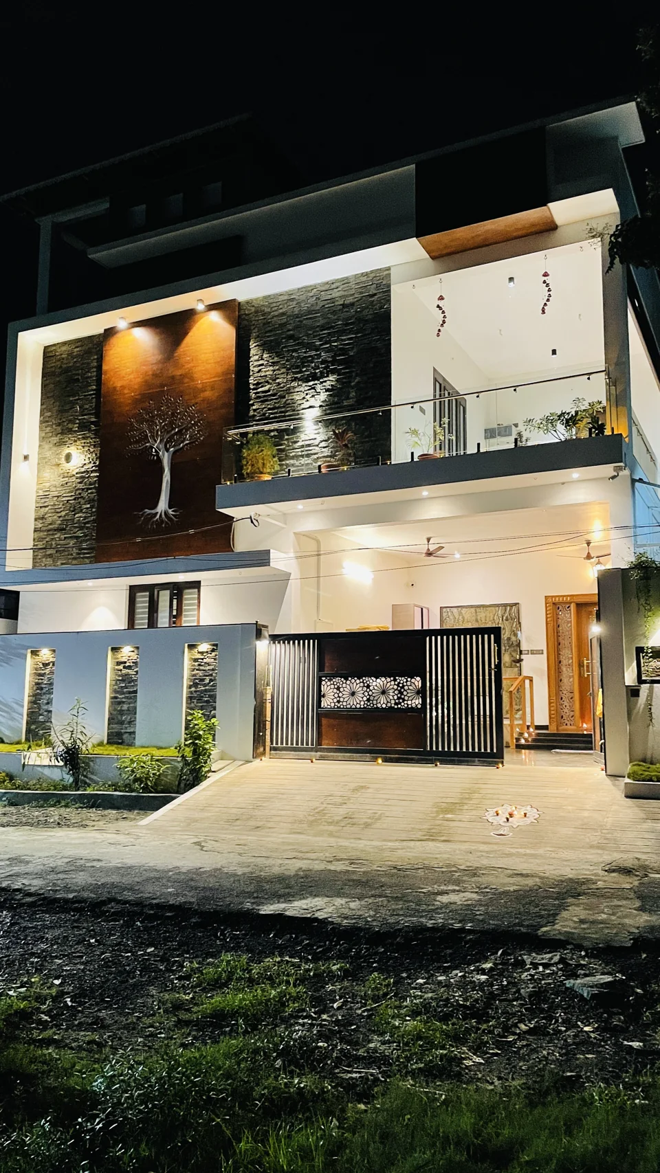 Residential facade at night with warm exterior lighting and a balcony