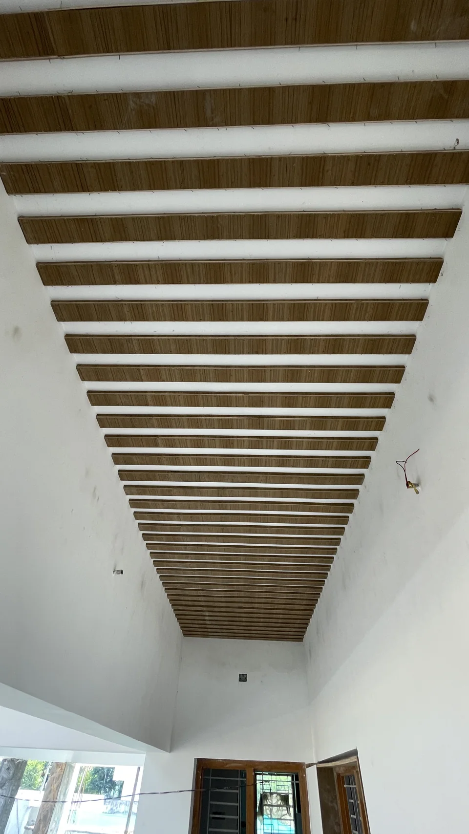 Long ceiling of evenly spaced timber slats running down a corridor